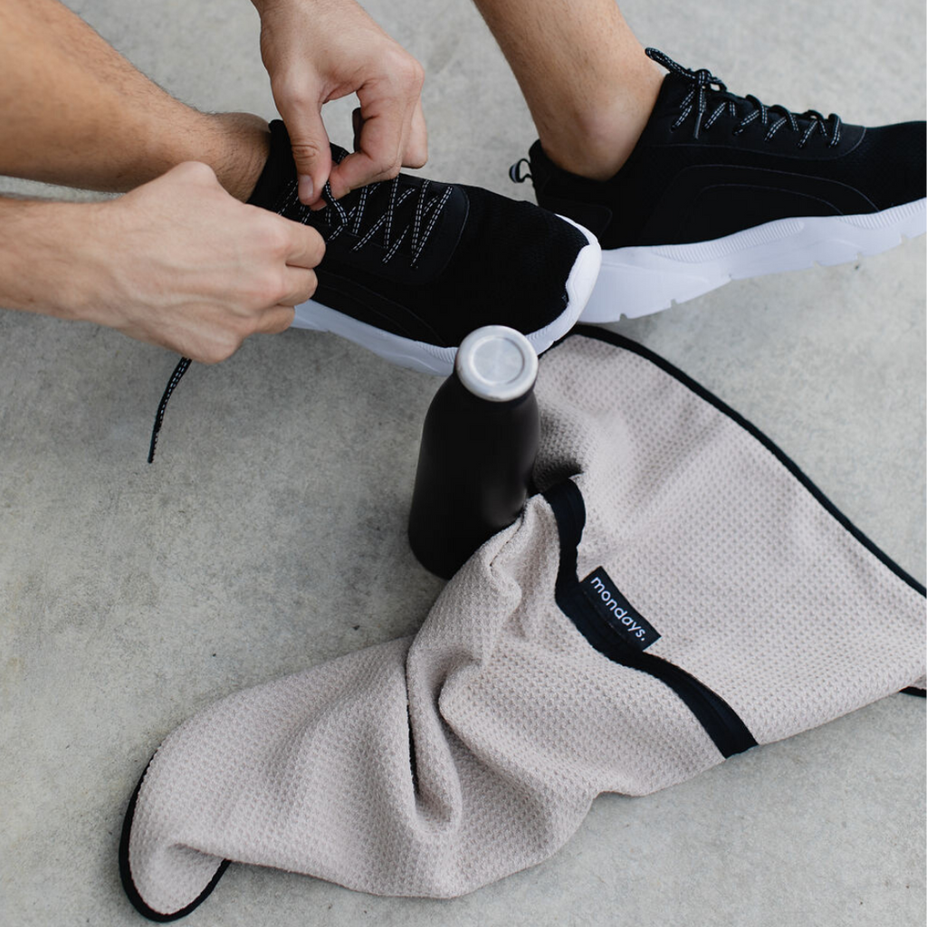 Man tying shoes with microfiber gym towel and drink bottle
